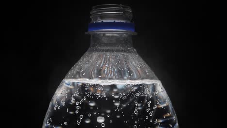 A-bottle-of-carbonated-water-is-unscrewed-by-hand-on-a-black-background
