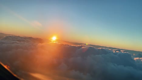Front-view-of-an-airplane-turning-above-the-clouds-at-sunset