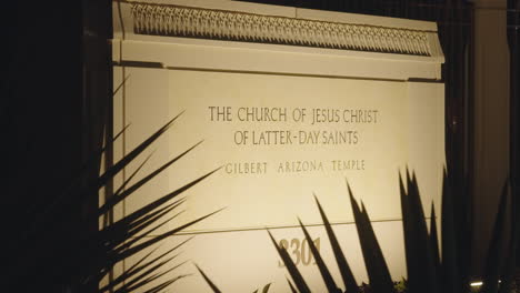 Sign-of-The-Church-of-Jesus-Christ-of-Latter-Day-Saints-LDS-Mormon-Temple-Church-Building-at-Night-Illuminated-by-Warm-Light-in-Gilbert,-Arizona