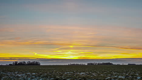 Sunrise-time-lapse-over-farmland-field-of-harvested-crops-in-autumn-or-winter-with-some-snow-on-the-ground