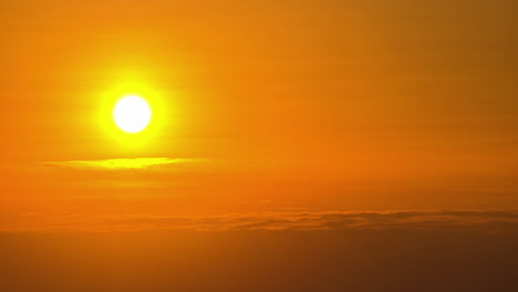 Bright,-fiery,-yellow-sun-as-it-descends-through-the-sunset-haze-in-a-golden-time-lapse