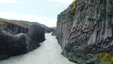 Scenic-aerial-along-gorge-with-glacial-river---basalt-rock-formations,-Studlagil
