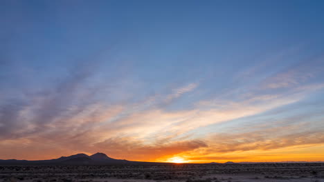 Colorful-blue-and-golden-sunrise-in-the-Mojave-Desert-with-the-mountains-in-silhouette---wide-angle-static-time-lapse