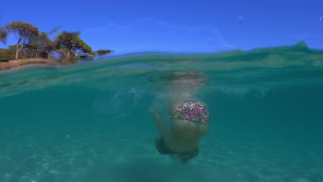 Halbe-Unterwasserszene-Eines-Kleinen-Mädchens-Mit-Tauchermaske,-Das-Im-Meerwasser-Des-Palombaggia-strandes-Auf-Der-Korsika-insel-Springt