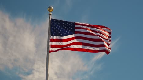 Ein-Niedriger-Winkelschuss-Der-Flagge-Der-Usa,-Die-Sich-Gegen-Einen-Bewölkten-Blauen-Himmel-Windet