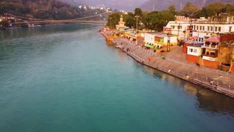 Das-Mit-Religiösen-Tempeln-Gefüllte-Flussufer-Des-Heiligen-Ganges-Am-Abend-Wird-Am-15.-März-2022-In-Rishikesh-Utrakhand,-Indien,-Aus-Der-Luft-Aufgenommen