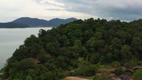 Cinematic-drone-flyover-mountain-hill,-Teluk-Batik-beach-reveals-Pangkor-island-across-the-water,-straits-of-malacca,-Lumut,-Perak,-Malaysia,-Southeast-Asia