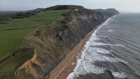 Aerial-jib-up-showing-the-long-Charmouth-Beach-and-the-incredible-cliff-sides-near-Dorset,-UK