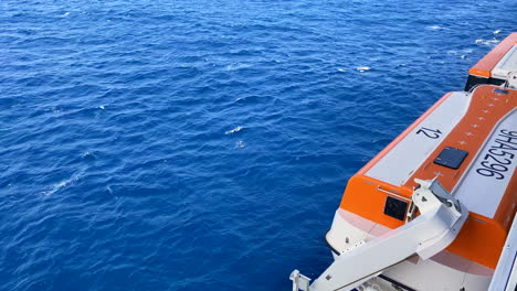 Blick-Auf-Das-Orangefarbene-Rettungsboot-Für-Kreuzfahrtschiffe,-Während-Das-Schiff-In-Ruhiger-Blauer-See-Segelt