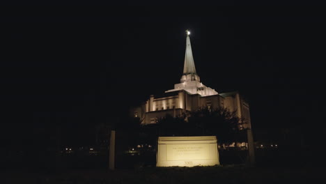 LDS-Mormon-Temple-in-Gilbert,-Arizona-with-Church-Building-Sign-at-Night-|-Moon-Backlighted-the-Angle-Moroni-at-top-of-Spire