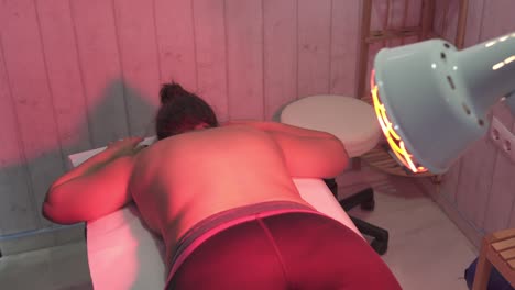 Rotating-shot-of-a-woman-lying-face-down-receiving-treatment-in-a-small-clinic