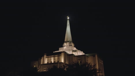 Mormonisches-Kirchengebäude-Bei-Nacht-Mit-Vögeln,-Die-Um-Die-Turmspitze-Herumfliegen,-Und-Dem-Engel-Moroni,-Der-Vom-Mond-Im-Hintergrund-Beleuchtet-Wird-|-Lds-tempel-In-Gilbert,-Arizona