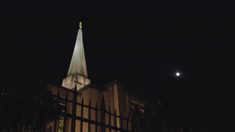 Birds-flying-around-the-Spire-of-a-LDS-Mormon-Temple-Church-Building-at-Night-with-the-Moon-in-the-Background-|-Gilbert,-Arizona