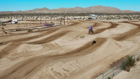 Motorcycles-racing-on-an-a-dirt-racecourse-with-the-Mojave-Desert-in-the-background---slow-motion-aerial-view
