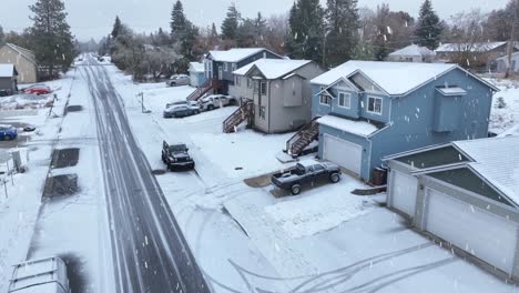 Aerial-view-of-a-neighborhood-covered-in-snow-during-a-winter-storm-with-active-flakes-falling