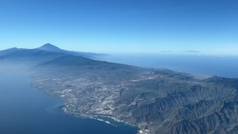 Aerial-view-from-a-jet-cockpit-of-Tenerife-Island,-Santa-Cruz-city-and-the-Teide-volcano,-in-a-splendid-winter-moorning,-with-a-deep-blue-sky