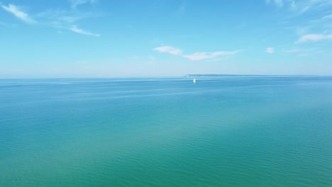 Aerial-Sailboat-in-Distance-with-Blue-Water