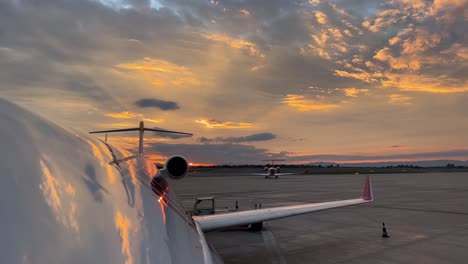 Upper-jet-fuselage-view-just-before-sunset-with-a-beautiful-winter-sky-with-the-sky-reflected-in-the-plane,-and-another-plane-taxing