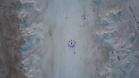 Sich-Drehende-Luftaufnahme-Eines-Salzfeldes-Mit-Einer-Gruppe-Von-Menschen,-Die-Auf-Dem-Boden-Liegen-Und-In-Meditation-Einen-Kreis-Bilden