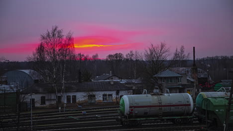 Blood-red-sunset-sky-above-old-industrial-rail-way-station,-fusion-time-lapse