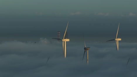 Cinematic-Aerial-Drone-Shot-of-Wind-Turbines-above-The-Clouds-During-Sunset