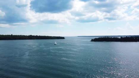 Wide-Aerial-of-Sailboat-and-forested-islands---Hessel,-Michigan---Lake-Huron