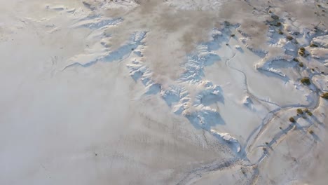 Bewegliche-Luftaufnahme-Eines-Salzfeldes,-Schneebedecktes-Feld-Mit-Wenig-Vegetation