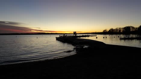 Beach,-lake-sunset-with-a-man-walking-on-a-pontoon