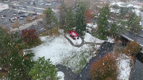 Aerial-view-of-snow-actively-falling-on-the-big-red-wagon-at-Spokane's-waterfront-park