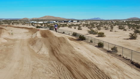 Motorcyclist-takes-a-long-jump-on-a-dirt-track-in-slow-motion---aerial-view