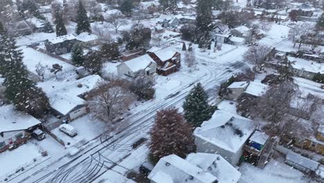 Drone-shot-of-houses-covered-in-snow-with-snowflakes-actively-falling