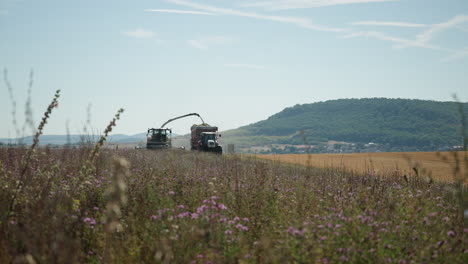 View-Of-Combine-And-Tractor-Driving-Slowly-Across-Field-In-Rhön-Grabfeld,-Germany