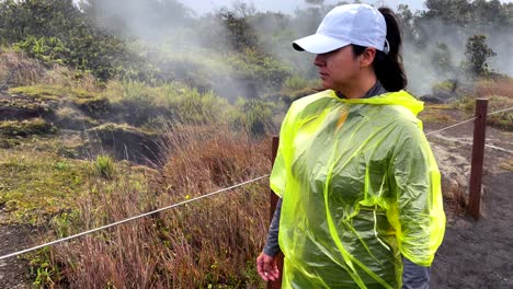 Hispanic-woman-walking-on-the-outside-rim-of-Mauna-Loa-volcano-in-Hawaii,-sulfur-vapors-smoking-grounds