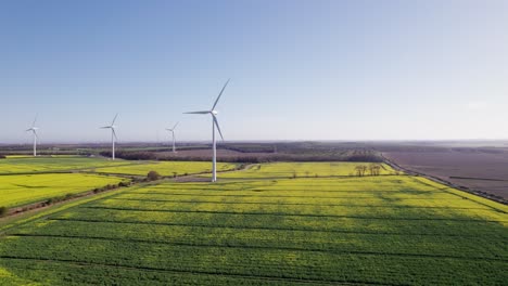 Drone-shot-tracking-left-of-wind-turbines-on-a-sunny-day,-wide,-aerial