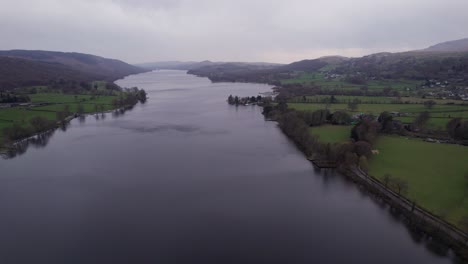 Drone-shot-panning-over-a-lake-on-a-dark-and-moody-day,-wide,-aerial