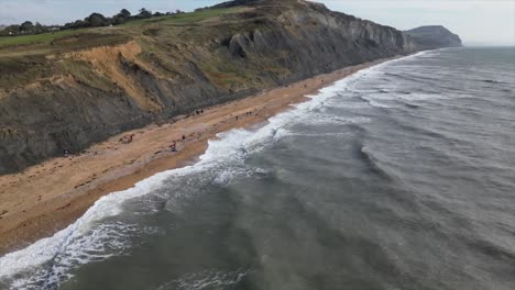 Aerial-jib-up-of-the-incredible-Charmouth-Beach-with-its-massive-cliff-sides