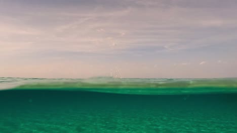 Geteilte-Perspektive-Der-Unterwasseroberfläche-Eines-Segelschiffs,-Das-Mit-Gesenkten-Segeln-Am-Horizont-Festgemacht-Ist