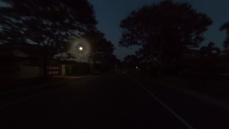 Rear-facing-night-driving-point-of-view-POV-for-interior-car-scene-green-screen-replacement---a-quiet-and-narrow-suburban-street-with-trees-and-right-hand-bend