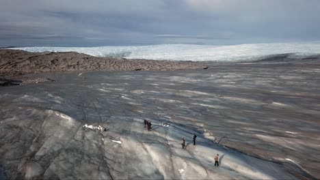 Aerial-view,-fly-over-people-walking-to-the-left-on-the-icecap-at-point-660,-just-outside-Kangerlussuaq,-Greenland