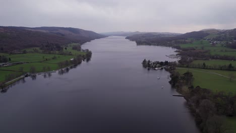 High-drone-shot-pulling-back-over-a-lake-on-a-dark-and-moody-day,-wide,-aerial