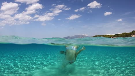 Young-little-girl-somersault-back-flip-in-clear-sea-water-of-Saleccia-exotic-beach-in-Corsica-island,-France