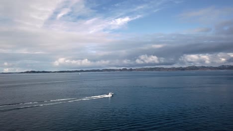 Aerial-view-over-Greenlandic-water,-where-a-motorboat-is-sailing,-to-the-right