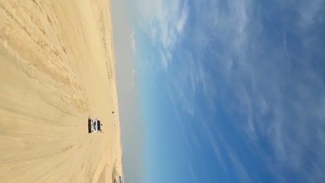 Vertical-video-4x4-vehicles-driving-along-desert-sand-dunes-landscape,-Qatar