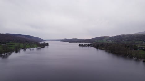 Drone-shot-pulling-back-over-a-lake-on-a-dark-and-moody-day,-wide,-aerial