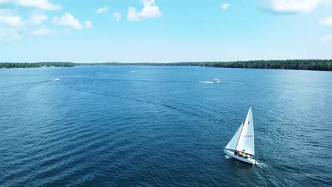 Following-Wide-Aerial-Sailboat-sailing-in-sun-during-summer---Hessel,-Michigan