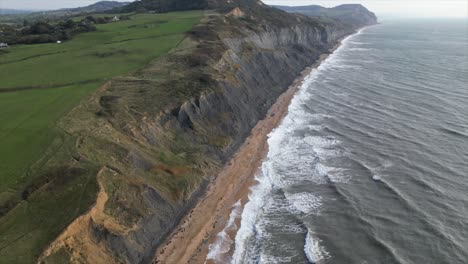 Aerial-tilt-up-revealing-incredible-cliff-sides-along-the-Charmouth-Beach-near-Dorset,-UK