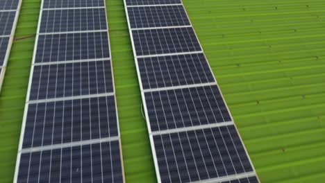 Renwable-energy-Solar-Panels-installed-on-green-warehouse-roof,-aerial-dolly-in