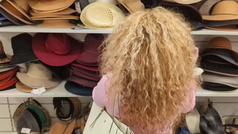 stunningly-beautiful-Latin-woman-with-long-hair-goes-hat-shopping-in-a-stack-of-hats-that-are-on-sale-at-a-clothing-retail-store