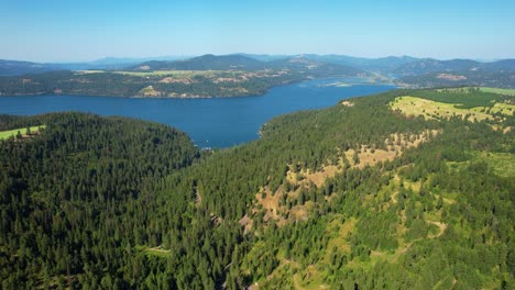Aerial-drone-shot-of-a-large-lake-in-between-mountains-and-green-forest