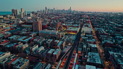 following-cta-holiday-train-decorated-in-chistmas-on-Brown-Lane-railroad-and-tilting-up-with-an-epic-chicago-skyline-view-at-sunset-4k